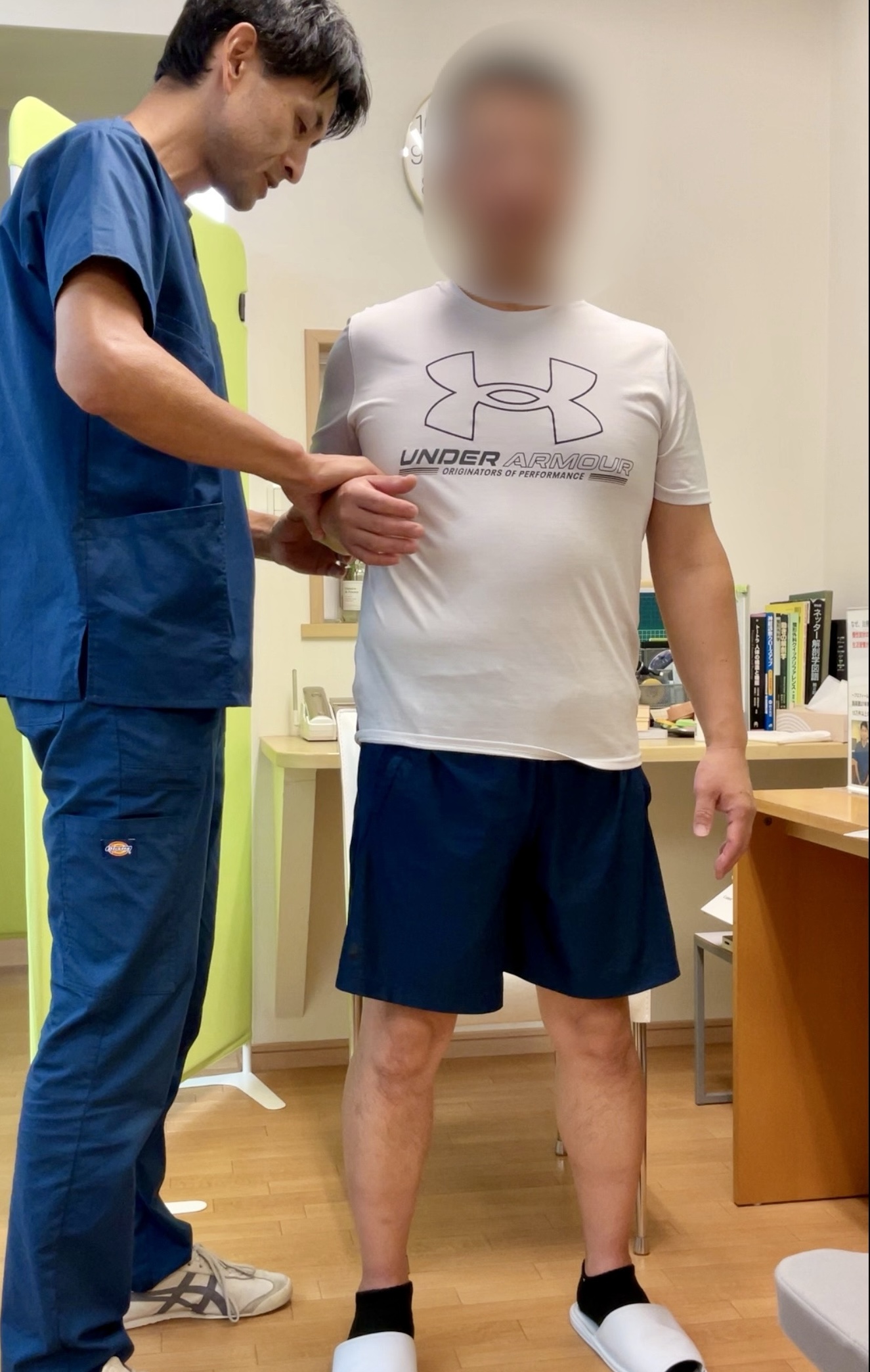 施術者がKさんの肩の動きや筋反射を確認し、痛みの出る角度や程度を評価している検査中の様子。