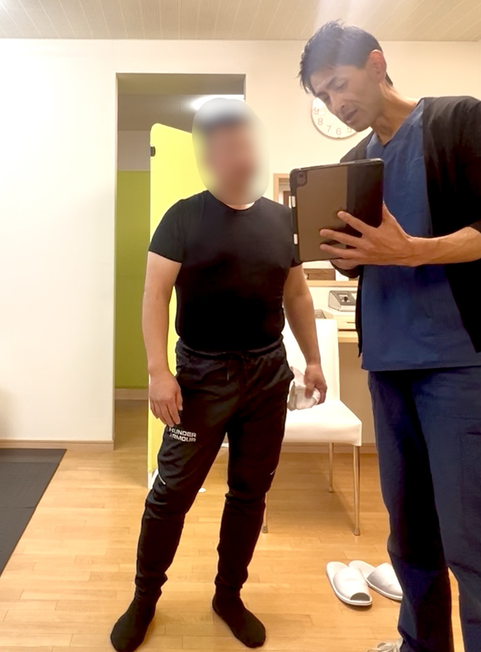 施術者がタブレットを使ってKさんの動きの映像を確認しながら、動作のクセや改善点を説明している場面。